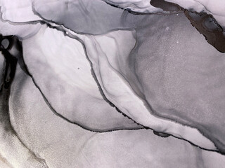 Abstract silver art — black and white background with beautiful smudges and stains made with alcohol ink and silver pigment. Fragment of art with grey fluid texture resembles watercolor or aquarelle.