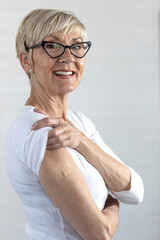 Proud mature woman smile after vaccination with bandage on arm