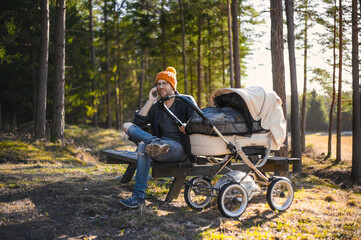 portrait of attractive nerd    with glasses in the forest  walks with a baby. Happy fatherhood with the wagon