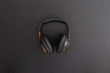 Headphones on black leather background. Music concept. Flat lay composition. Top view.