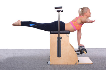 A 20-year-old trainer is practicing Pilates on an elevator chair, lying on her stomach supporting...