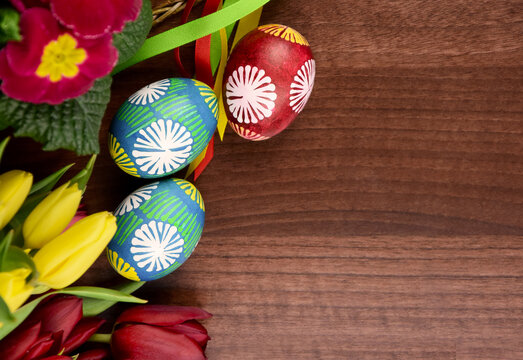 Beautiful hand painted easter eggs with spring flowers top view stock images. Easter decoration with colored eggs and fresh flowers stock photo. Traditional unique easter eggs on a wooden table images