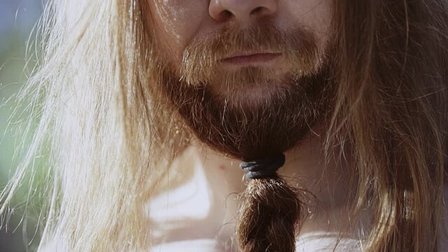 The light from the knife blade falls on the face of a bearded, long-haired guy. Close-up shooting