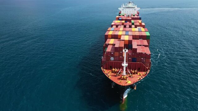 Aerial drone top view video of fully loaded container ship cruising open ocean sea for logistics import export, shipping or transportation