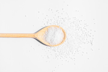 White sea salt on wooden spoon. Isolated on white background. Rustic appearance.