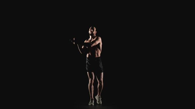 Male athlete jumping on skipping rope on a black background