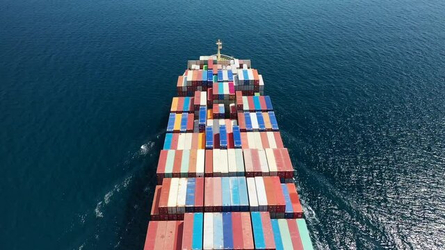 Aerial drone top view video of fully loaded container ship cruising open ocean sea for logistics import export, shipping or transportation