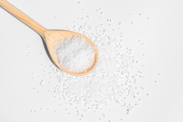 White sea salt on wooden spoon. Isolated on white background. Rustic appearance.