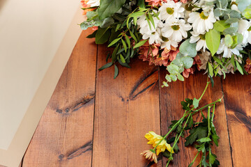 A bouquet of multi-colored chrysanthemums lies on a wooden table.