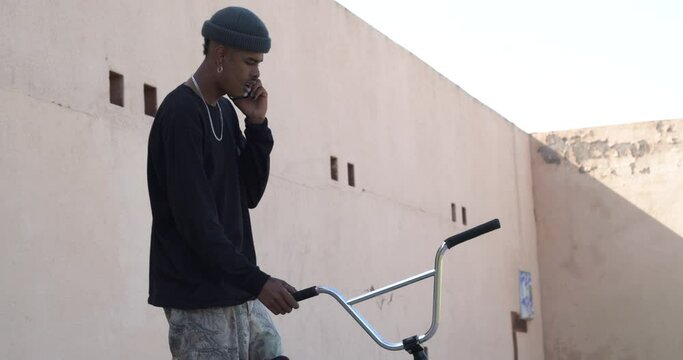 Young afro man rapper talking on the phone in the street.Young millennial urban lifestyle