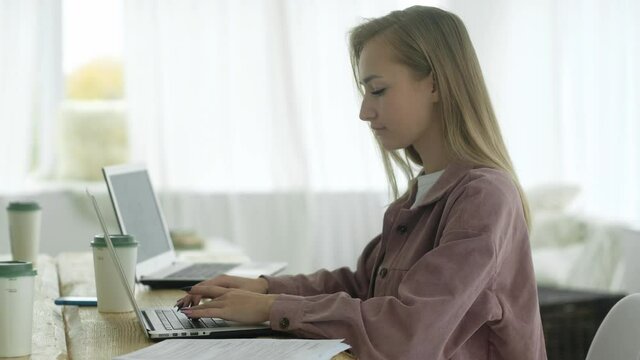 Businesswoman works in office on computer, typing text with fingers. Secretary assistant blonde woman is typing document on laptop doing online work in office or browsing web. takeaway coffee on table