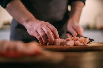 A male chef prepares fresh meat at home in the kitchen..