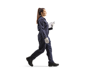 Full length portrait of a female worker in a uniform walking and holding a clipboard
