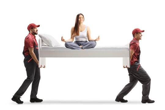 Movers carrying a bed with a young female in pajamas sitting in a yoga pose