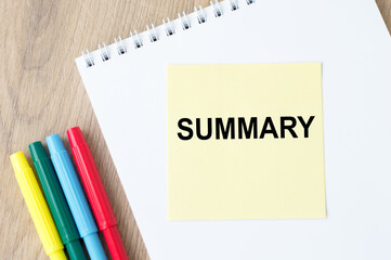 Yellow note card on notepad with word Summary, business concept