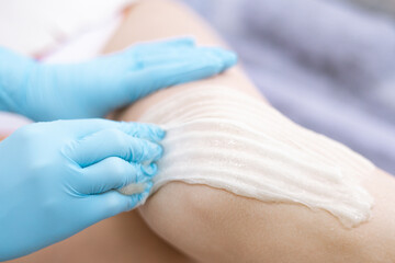 female legs hair removal with  sugaring procedure in beauty salon