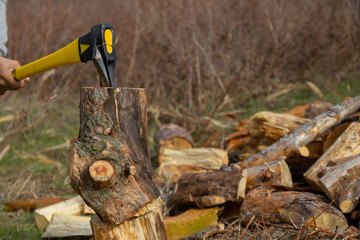 An ax with a yellow-black handle, chopping wood.