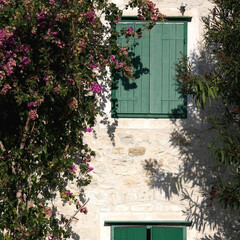 Traditional Mediterranean house with wooden window shutters and flowers.