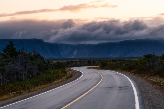 Scenic curvy road in the Canadian Landscape. Dramatic Colorful Sunrise Artistic Render. Taken in Gros Morne National Park, Newfoundland, Canada.