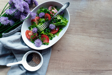 Spring salad on plate with vegetables for vegetarian on a wooden table with copy space. Healthy breakfast with fresh salad and herb. Top view.