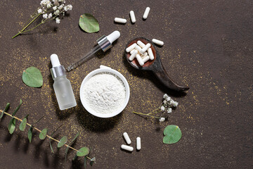 Organic collagen products for skin care, beauty and healthy lifestyle. Collagen powder, capsules and serum on dark rustic background decorated with fresh eucalyptus leaves.