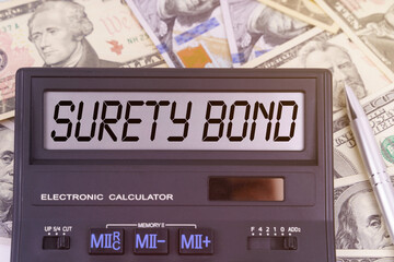 On the table are dollars and a calculator on the electronic board which says SURETY BOND