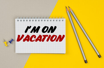 On a yellow-gray background are pencils, buttons and a notebook in which it is written - I M ON VACATION