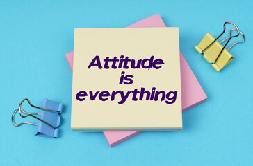 On the table are paper clips, note paper with text - Attitude is everything