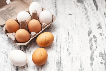 Close-up view of raw chicken eggs in egg box on white wooden background