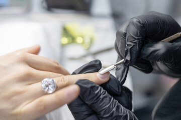 Obraz na płótnie Canvas process of manicure in the salon on long nails, pushing back the cuticle with a special tool