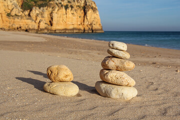 pile of pebbles on a sandy beach with cliff, balance, zen concept