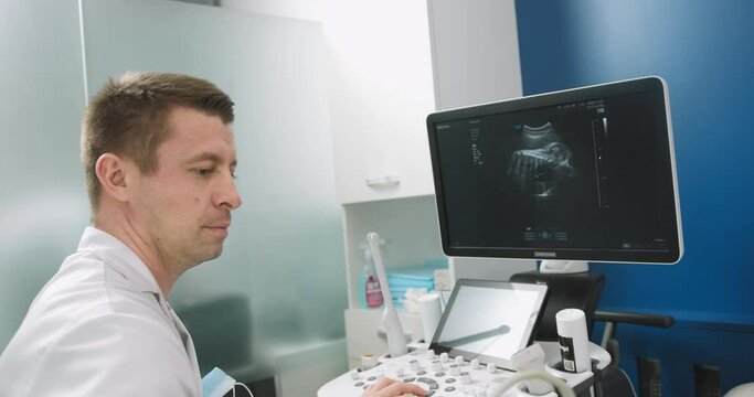 Doctor fertility specialist uses ultrasound equipment while checking pregnant woman. Prenatal testing with ultrasound. Doctor doing 3d ultrasound on belly in clinic. Process of fetal ultrasonography