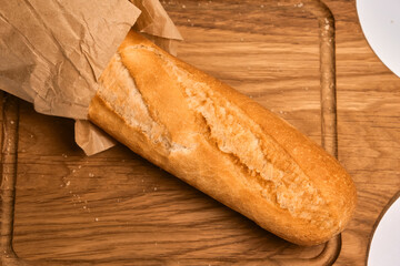 French bread baguette cut on vintage wooden bread board with knife.
