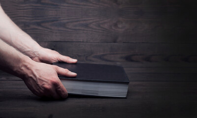 Holy Bible in the hands of a man. On a wooden background.