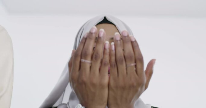 Modern African Muslim woman makes traditional prayer to God against white backgorund