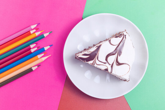 Homemade Piece Of Cake And Pencils On A Colorful Background. Top View, Copy Space.