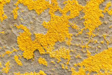 Old wall with yellow peeled weathered paint