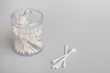 Ear cotton buds in a jar and scattered on white paper