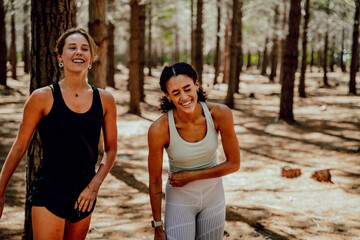 Two female friends laughing together standing in forest 