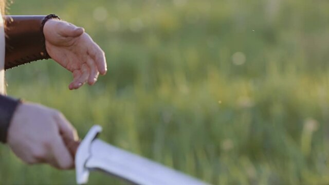Close-up of the hands of a warrior guy who throws a large knife from hand to hand. Slow motion images