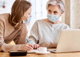 Anonymous women in masks using laptop and taking notes at home