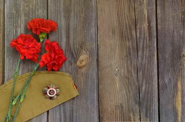 Victory Day.Order of the red star with the Russian inscription Patriotic war on a wooden background with red carnations.Celebration on may 9