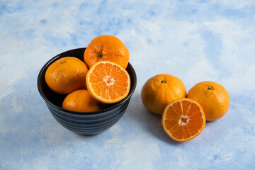 Clementine mandarins in bowl on blue background
