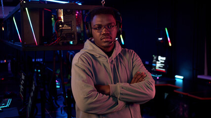 An african gamer poses for the presentation of his team at the esports championship, looks at the camera with his arms folded