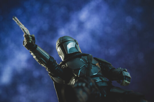 NEW YORK USA - APRIL 8 2021: Low angle of bounty hunter Din Djarin pointing blaster with star filled sky - from Disney Plus The Mandalorian  - Hasbro action figure