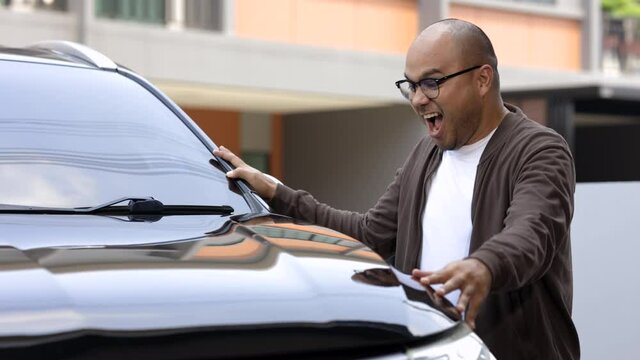 Young handsome asian man getting the new car. He hugged his car and was very happy. Buy or rent car concept.