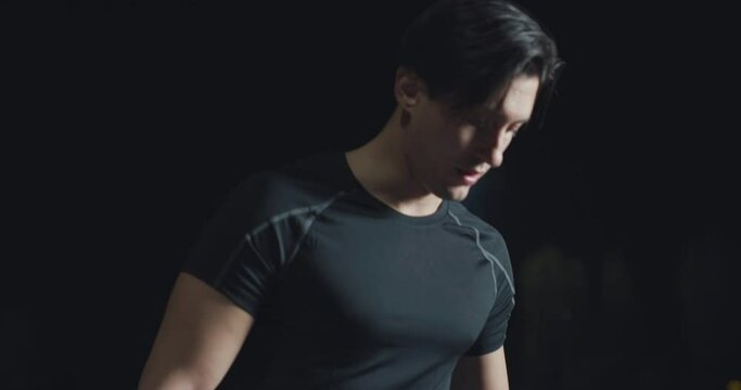 Cinematic close up shot of disable man with legs prosthesis is warming up before run with dedication on car track at night. Concept of handicapped people active lifestyle, determination, motivation.