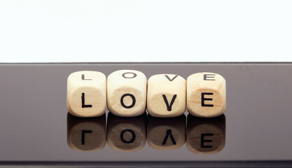 On wooden cubes the word love, lie on a reflective surface