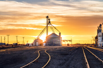 Grain storage on railroad tracks with a beautiful sunset