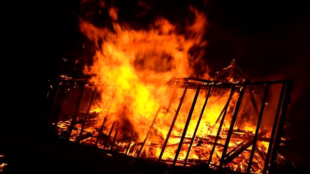 Burning wooden building at night, close up view